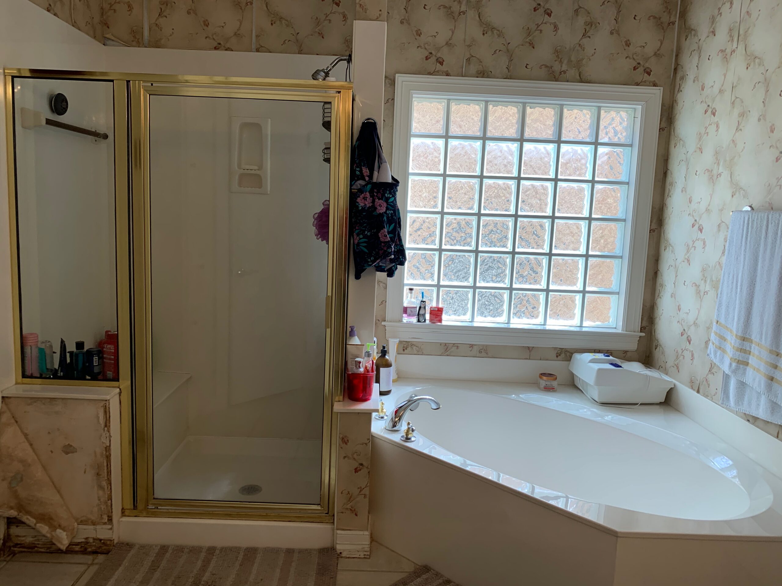 Dated bathroom before ADA remodel with brass fixtures and wallpaper Austin TX